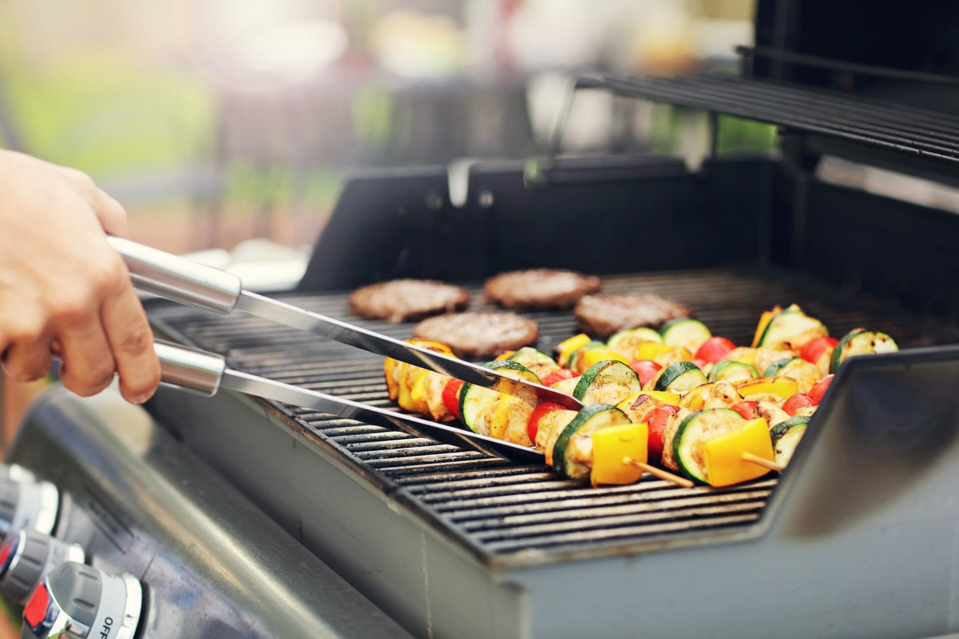 a man grilling vegetables on a gas grill