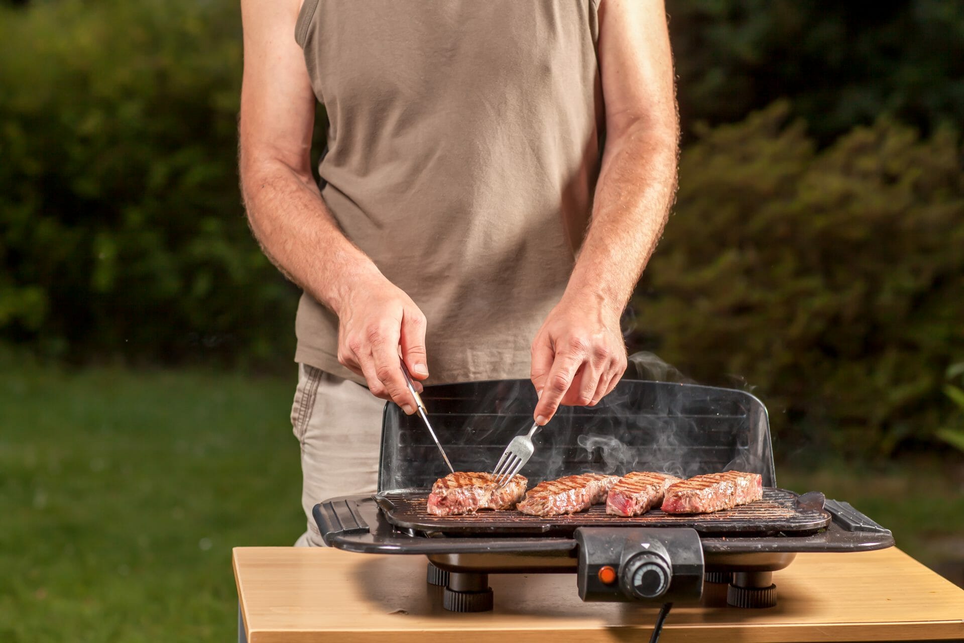 a man flipping meat on an electric grill