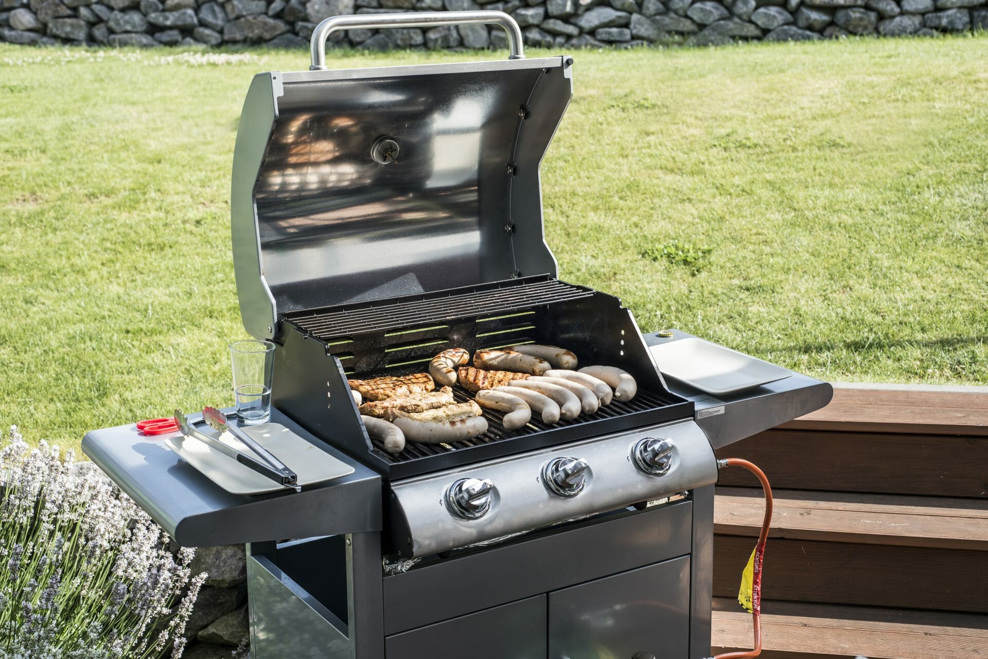 gas grill outdoors with meat on it